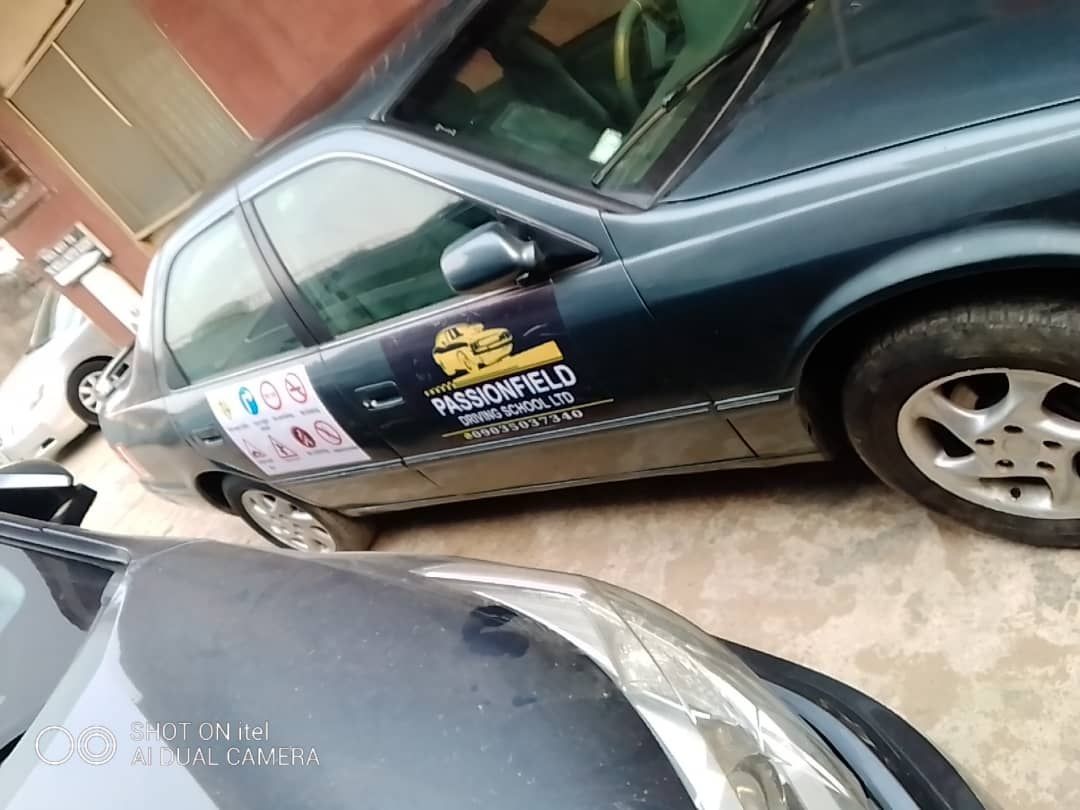 Car with Passionfield Driving School sign parked on a concrete surface.