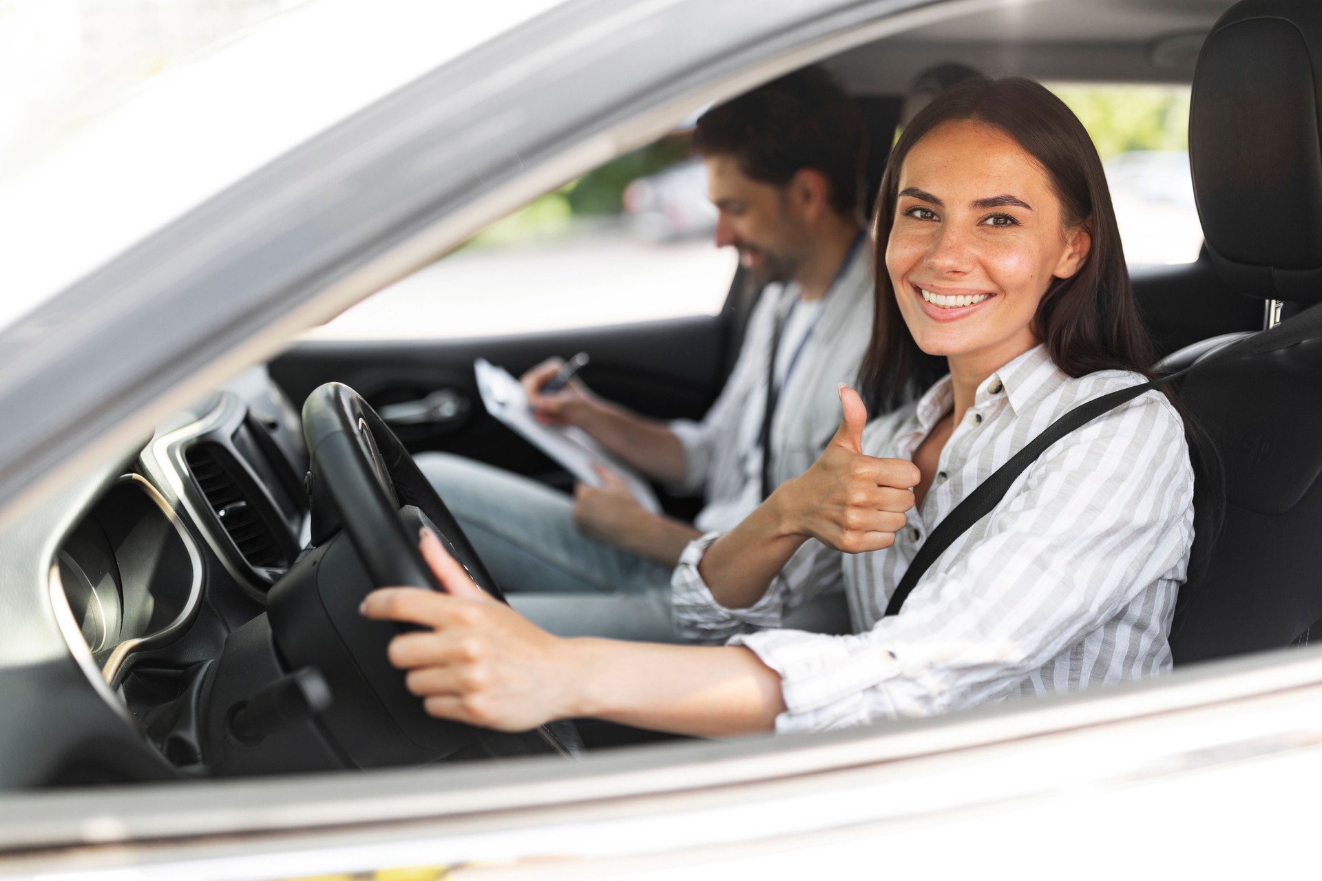 Happy woman passing exams at driving school, showing thumb up