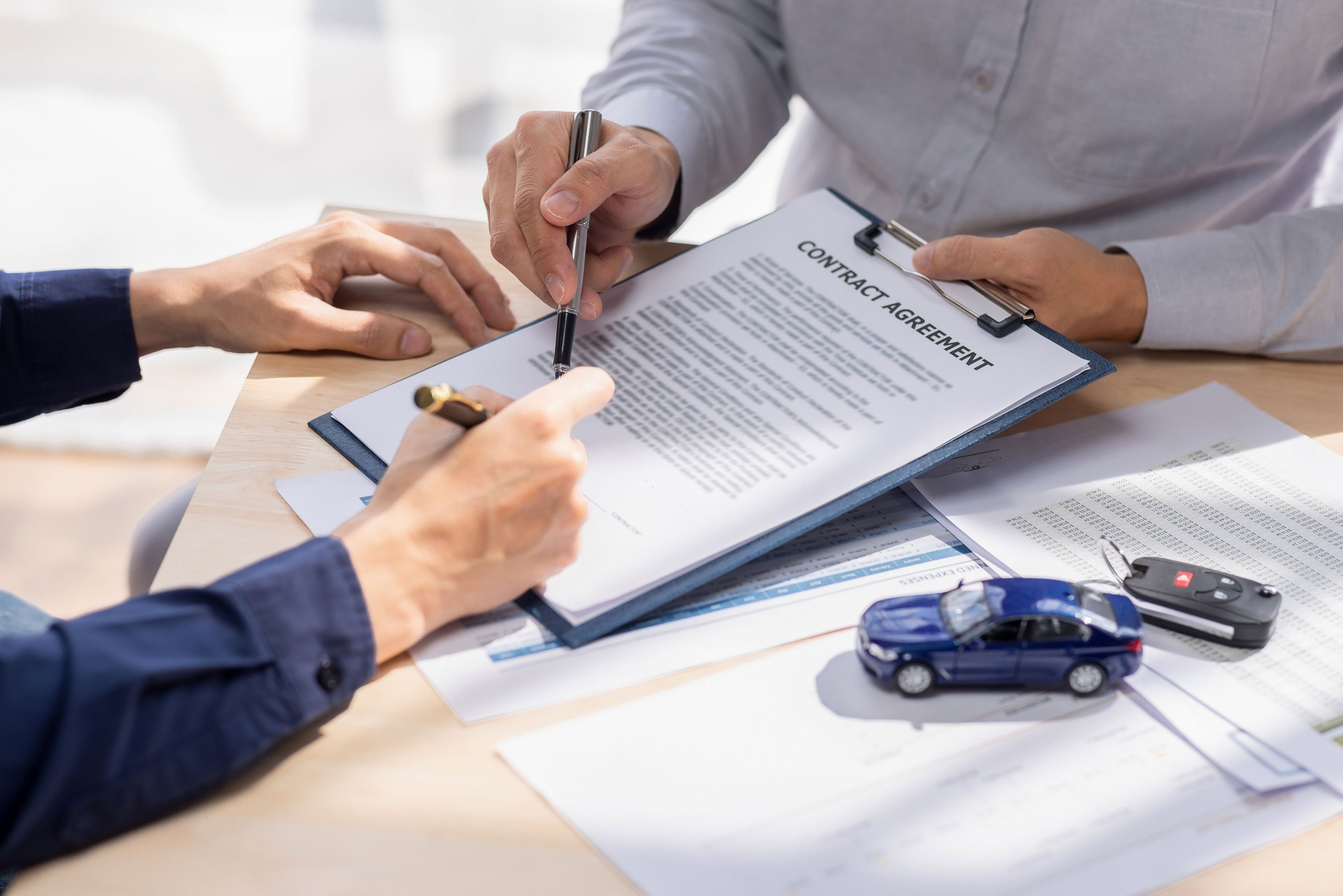 Car Insurance document or lease concept the car broker assisting his customer and explaining the detail of the car contact. Car key Buying or selling signing .